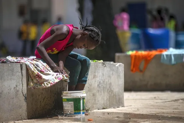 A girl washes a piece of clothing in a school turned into a shelter for families forced to leave their home in Cite Soleil due to clashes between armed gangs, in Port-au-Prince, Haiti, Saturday, July 23, 2022. (Photo by Joseph Odelyn/AP Photo)