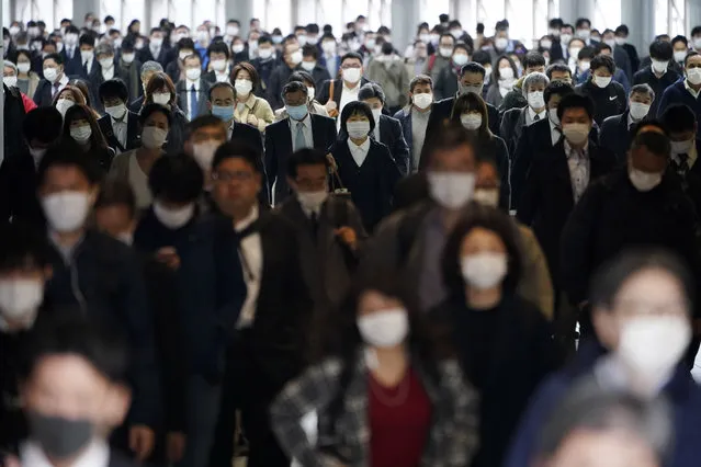 A station passageway is crowded with commuters wearing face mask during a rush hour in Tokyo Monday, April 27, 2020. Japan's Prime Minister Shinzo Abe expanded a state of emergency to all of Japan from just Tokyo and other urban areas as the virus continues to spread. (Photo by Eugene Hoshiko/AP Photo)