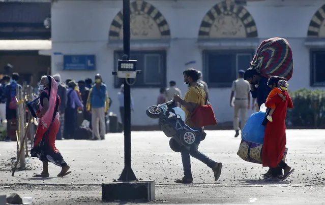 People from other states trying to get back to their homes arrive to board trains at the Chhatrapati Shivaji Maharaj Terminus in Mumbai, India, Tuesday, May 19, 2020. The number of coronavirus cases in India has surged past 100,000, and infections are now on the rise in the home states of the migrant workers who left cities and towns during the nationwide lockdown. (Photo by Rajanish Kakade/AP Photo)