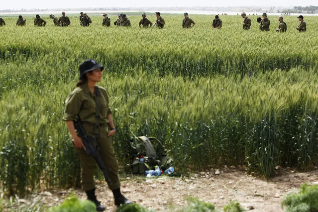An Israeli soldier guards as her comrades search for remains at the site of a helicopter crash in a field near Kibbutz Revadim in southern Israel March 12, 2013. (Photo by Amir Cohen/Reuters)