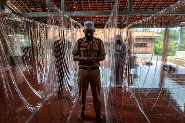 People pray between plastic separation curtains to prevent the spread of the coronavirus disease (COVID-19) in Semarang, Central Java Province, Indonesia, May 18, 2020. (Photo by Aji Styawan/Antara Foto via Reuters)