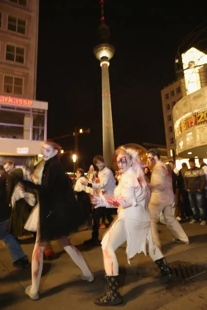 Zombie enthiusiasts dance near the broadcast tower at Alexanderplatz during a “Zombie Walk” in the city center on October 27, 2012 in Berlin, Germany. Approximately 150 zombies, who had organized themselves through Facebook, walked and limped across Alexanderplatz, growled and moaned at passersby and performed their jerking dances. (Photo by Sean Gallup)