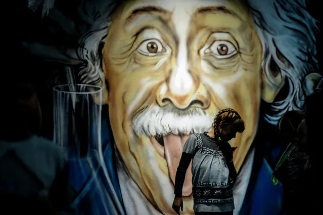 A girl walks in front of a graffiti depicting German-born physicist Albert Einstein at a museum of entertaining science in Minsk on October 31, 2017. (Photo by Sergei Gapon/AFP Photo)