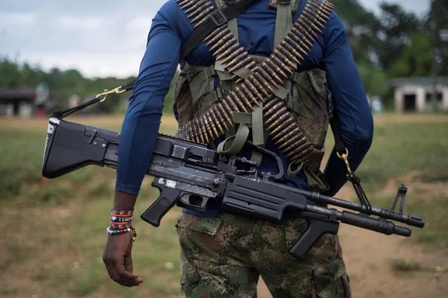 A member of the “Omar Gomez” Western War Front of the National Liberation Army (ELN) guerrilla carries his machine gun in a camp on the banks of the San Juan River, Choco department, Colombia, on November 19, 2017. Colombia's landmark peace deal with Marxist FARC rebels was supposed to mean peace for all but it has made little difference to indigenous and Afro-Colombian minorities, Amnesty International said on November 22, 2017. Although the agreement between the Colombian government and the FARC was signed, armed conflict is still very much the reality for millions across the country, said Salil Shetty, Secretary General at Amnesty International. (Photo by Luis Robayo/AFP Photo)