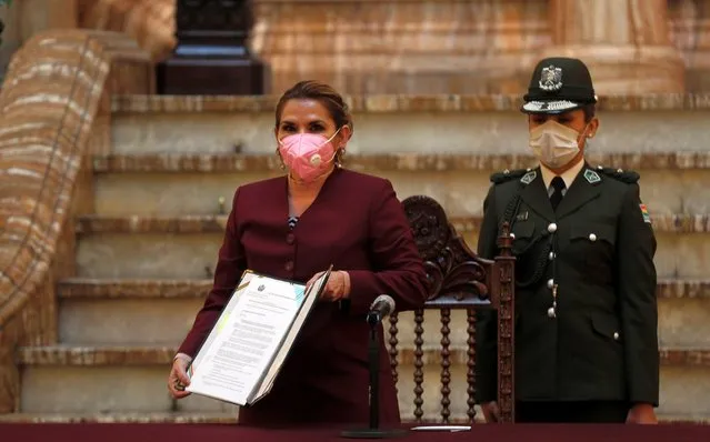 Bolivia's interim President Jeanine Anez, wearing a face mask amid the COVID-19 pandemic, poses for a photo holding the document that enacts a law that calls for elections on Oct. 18, at the government palace in La Paz, Bolivia, Thursday, August 13, 2020. Citing the ongoing COVID-19 pandemic, Bolivia's highest electoral authority delayed presidential elections from Sept. 6 to Oct. 18, the third time the vote has been delayed. (Photo by Juan Karita/AP Photo)