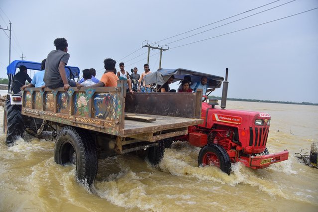 People ride a cart through a submerged road in Hojai district, Assam, India, on June 3, 2025. They are being relocated to safer areas after flooding submerged parts of their village following heavy rainfall. (Photo by Anuwar Hazarika/Middle East Images via AFP Photo)