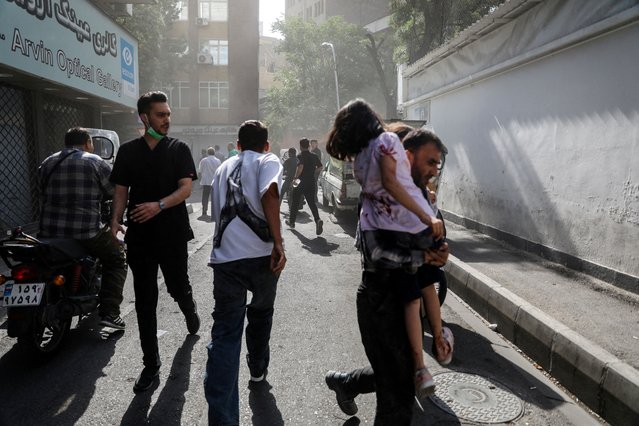 People run along a street amid smoke following the Israeli strikes on Iran, in Tehran, on June 15, 2025. (Photo by Hamid Amlashi/Reuters)