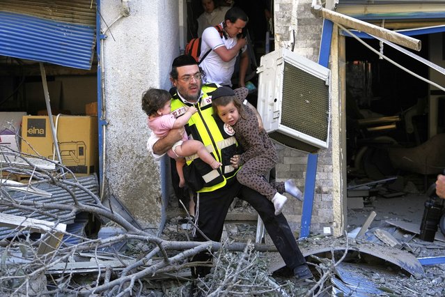 A rescue worker evacuates two children from the site where a missile launched from Iran struck in Haifa, Israel, Sunday, June 22, 2025. (Photo by Baz Ratner/AP Photo)
