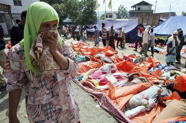 An Acehnese woman covers her nose as she walks past thousands of dead bodies in the Indonesian city of Banda Aceh in this December 27, 2004 file photo. (Photo by Reuters/Beawiharta)