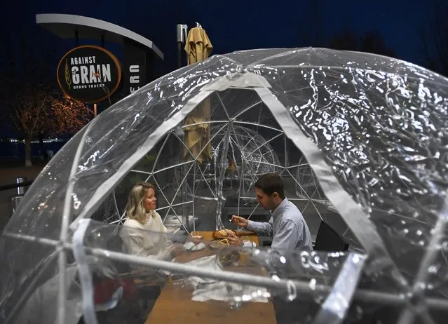 People enjoy outdoor dining in a weather proof dome pod at Against the Grain Urban Tavern during the COVID-19 pandemic in Toronto on Wednesday, October 21, 2020. (Photo by Nathan Denette/The Canadian Press via AP Photo)