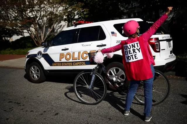 A counter-protester gestures in front of a police car as supporters of President Donald Trump demonstrate near the Republican National Committee building after Election Day, in Washington, November 5, 2020. (Photo by Hannah McKay/Reuters)