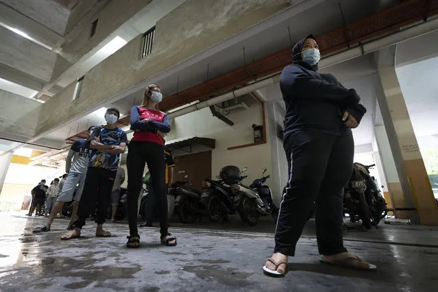 Residents wait in line as health ministry staff collect samples for coronavirus testing from residents at an urban area in Bandar Utama, outskirts of Kuala Lumpur, Malaysia Thursday, October 22, 2020. Malaysia restrict movements in its biggest city Kuala Lumpur, neighboring Selangor state and the administrative capital of Putrajaya from Wednesday in an attempt to curb a sharp rise in coronavirus cases. (Photo by Vincent Thian/AP Photo)