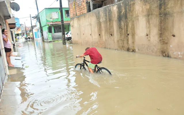 Boy riding a bicycle in the flooded area on the outskirts of the city of Salvador, on April 24, 2013. (Photo by Paula Fróes/BAPress/Estadão Conteúdo)