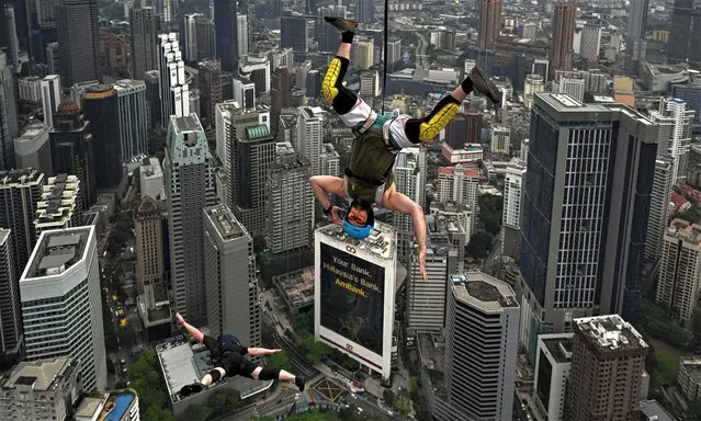 Base jumper Sean Devlin of the US (R) leaps from the 300-metre high open deck of Malaysia's landmark Kuala Lumpur Tower during the International Tower Jump in Kuala Lumpur on February 3, 2023. (Photo by Mohd Rasfan/AFP Photo)