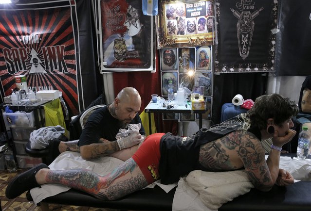 Argentinian tattoo artist Maico Migdal (L) works on a customer during a tattoo convention in Bucharest, Romania, 15 October 2016. (Photo by Robert Ghement/EPA)