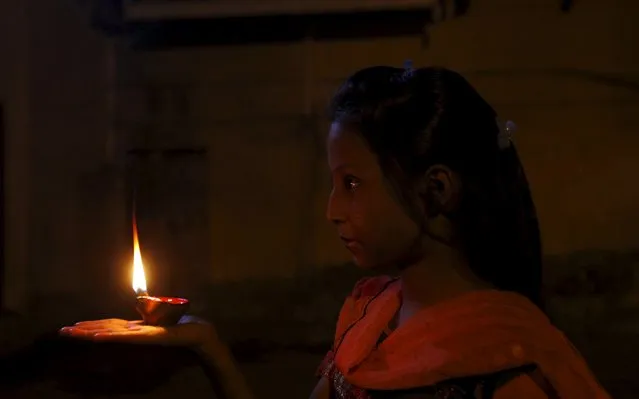 A girl holds an oil lamp in prayer during the Hindu festival of Diwali at the Shri Panchmukhi Temple in Karachi, Pakistan, November 11, 2015. (Photo by Akhtar Soomro/Reuters)