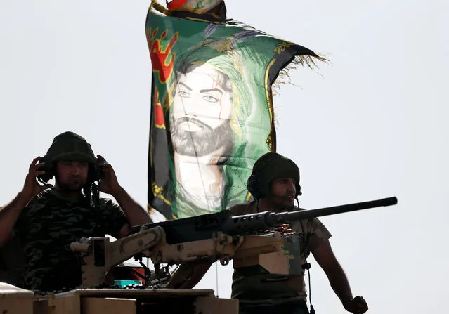 Iraqi special forces soldiers sit on top of an armoured vehicle next to a flag of Imam Hussein in Bartella, east of Mosul, Iraq October 20, 2016. (Photo by Goran Tomasevic/Reuters)