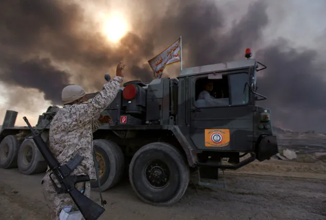 Iraqi army are seen in Qayyara, Iraq, October 22, 2016. The fumes in the background are from oil wells that were set ablaze by Islamic State militants. (Photo by Alaa Al-Marjani/Reuters)