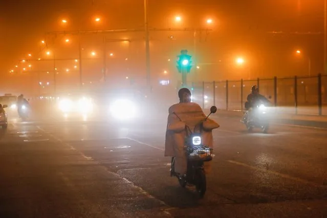 People wearing face masks ride scooters on a street in Beijing, China, 10 April 2023, as strong winds and sandstorm hit the city. Chinese meteorological authorities issued a yellow warning of sandstorm and strong wind weather on 10 April 2023. (Photo by Wu Hao/EPA/EFE/Rex Features/Shutterstock)