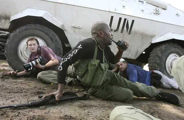 Reuters Congo correspondent David Lewis (L) takes cover under a U.N. armored car during machine gun and mortar fire in Kinshasa,Democratic Republic of the Congo, November 11, 2006. (Photo by Goran Tomasevic/Reuters)