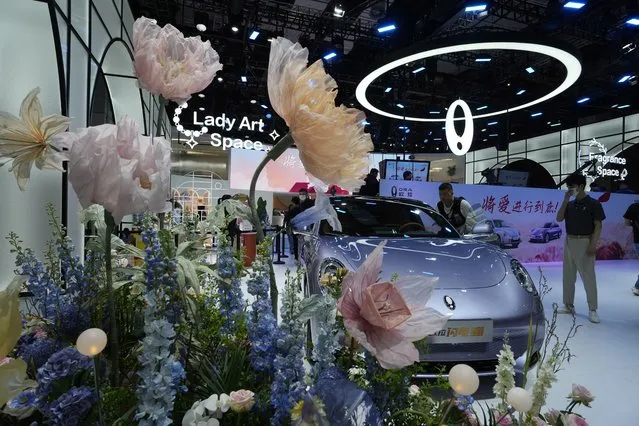Floral decorations frame a car from Ora, a Chinese electric car brand during the Auto Shanghai 2023 show at the National Exhibition and Convention Center in Shanghai, China, Tuesday, April 18, 2023. Global and Chinese automakers plan to unveil more than a dozen new electric SUVs, sedans and muscle cars this week at the Shanghai auto show, their first full-scale sales event in four years in a market that has become a workshop for developing electrics, self-driving cars and other technology. (Photo by Ng Han Guan/AP Photo)