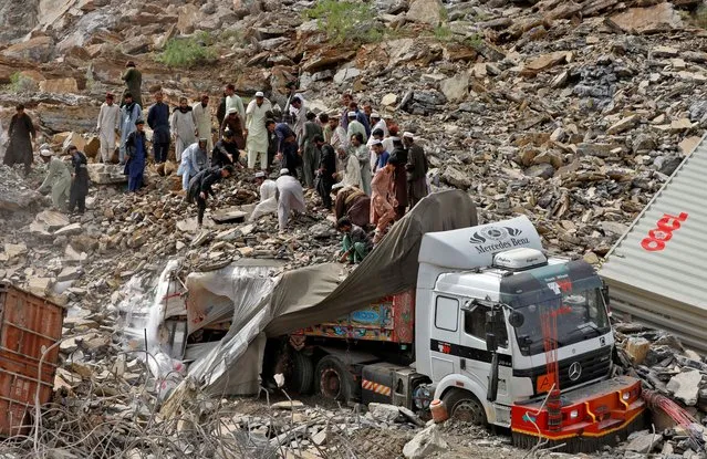 People search for survivors next to a damaged supply vehicle after a landslide close to the Torkham border, Pakistan on April 18, 2023. (Photo by Fayaz Aziz/Reuters)