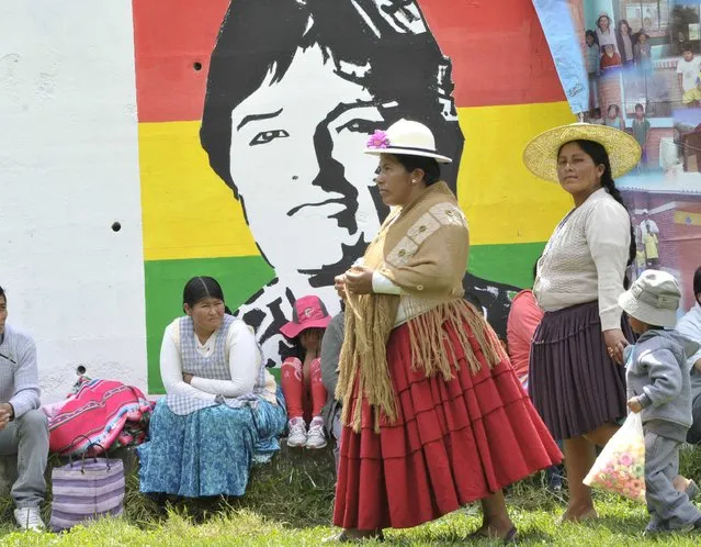 Women walk past a mural depicting Bolivia's President Evo Morales in Quime, southeast of La Paz, November 28, 2015. Morales visited Quime to inaugurate a new market building, according to local media. (Photo by Reuters/Bolivian Presidency)