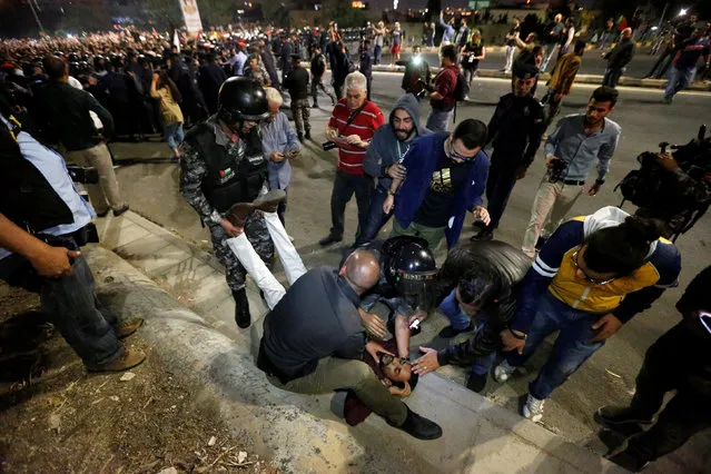 Jordanian security personnel and demonstrators help an injured protester during a protest in Amman, Jordan, June 2, 2018. Hundreds of Jordanians demonstrated in the capital Amman for a third consecutive day against a proposed income tax draft law aimed at widening the base of tax payers. (Photo by Muhammad Hamed/Reuters)