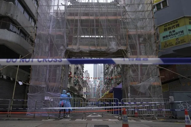 Government workers wearing personal protective equipment stand guard at the closed area in Jordan district, in Hong Kong, Sunday, January 24, 2021. Thousands of Hong Kong residents were locked down Saturday in an unprecedented move to contain a worsening outbreak in the city, authorities said. (Photo by Vincent Yu/AP Photo)