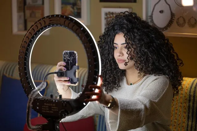Mariam Ashraf, a teacher and “natural hair influencer”, speaks before a phone on a tripod and lights during a live-stream at her home in Egypt's capital Cairo on March 22, 2022. “Shaggy”, “messy”, “unprofessional”. Natural curls were once looked down upon in Egypt, where Western beauty standards favoured sleek, straight locks. Now, things are changing. (Photo by Khaled Desouki/AFP Photo)