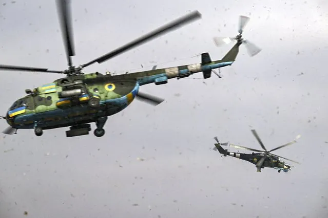 An Mi-24 (R) and an Mi-8 (L) helicopters take off for a mission against Russian targets on March 26, 2023, amid the Russian invasion of Ukraine. (Photo by Aris Messinis/AFP Photo)