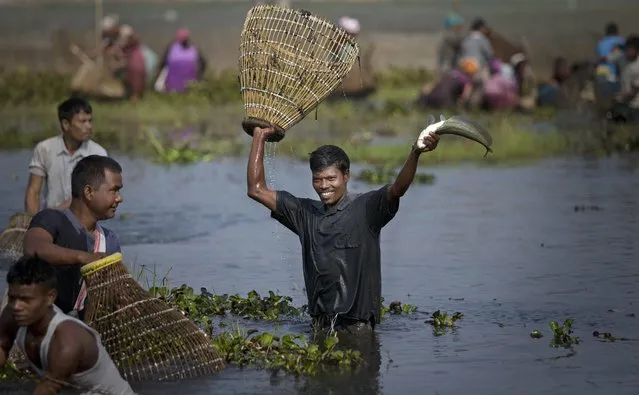 A tribal Tiwa man displays his catch during a community fishing event as part of the Jonbeel festival near Jagiroad, India, Friday, January 23, 2015. Tribal communities like Tiwa, Karbi, Khasi, and Jaintia from nearby hills come down in large numbers to take part in the festival and exchange goods through barter rather than money. (Photo by Anupam Nath/AP Photo)