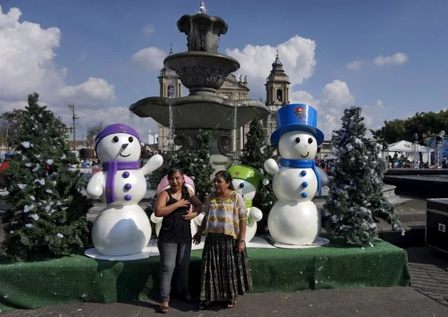 Two women pose for a picture in front of snowmen figures in downtown Guatemala City, December 13, 2015. (Photo by Jorge Dan Lopez/Reuters)