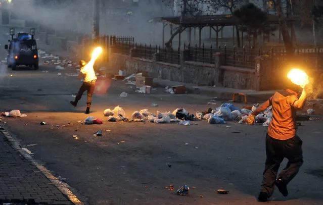 Masked men throw petrol bombs towards police who used water cannons and teargas to disperse people protesting against security operations against Kurdish rebels in southeastern Turkey, in Istanbul, Sunday, December 20, 2015. Security forces have killed more than 100 Kurdish rebels in last four days in southeast Turkey, news agencies' reports say. (Photo by Omer Kuscu/AP Photo)