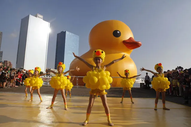 Girls dress as ducks as people gather to see a giant Rubber Duck by Dutch conceptual artist Florentijin Hofman at Glory Pier on September 19, 2013 in Kaohsiung, Taiwan. The “Rubber' Duck”, is traveling the world and will stop in Kaohsiung from September 19 to October 20. (Photo by Ashley Pon/Getty Images)