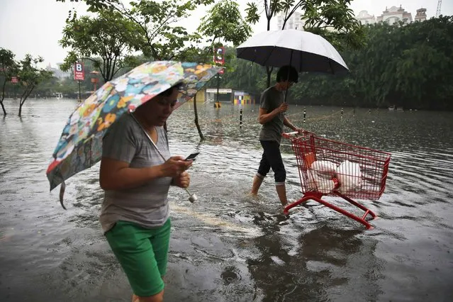 Lotte Mart customers wade across floodwaters at the car park in the flooded Kelapa Gading business district in Jakarta, January 23, 2015. Floods inundated several areas of Jakarta after heavy rains in the capital city, local media reported on Friday. (Photo by Reuters/Beawiharta)