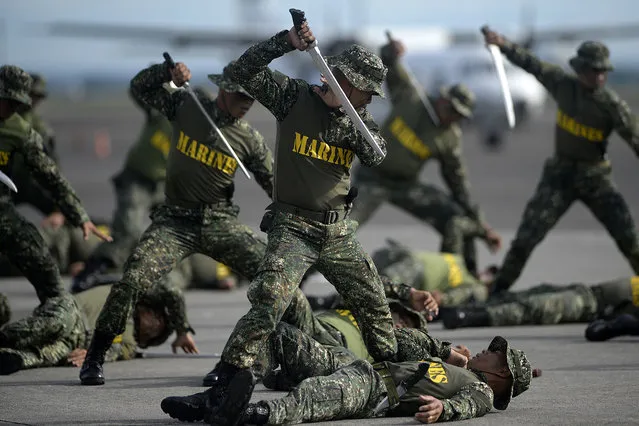 Philippine soldiers show off their close combat quarters skills using mock machetes during the Armed Forces of the Philippines (AFP) 80th anniversary celebration at Haribon Hangar, Air Force City, Clark Air Base, Pampanga, south of Manila on December 21, 2015. Philippine President Benigno Aquino promised on December 21 that 1.77 billion USD (83.9 billion pesos) allocated for  military modernisation projects would be spent by 2017 as the country faces a territorial dispute with China. (Photo by Noel Celis/AFP Photo)