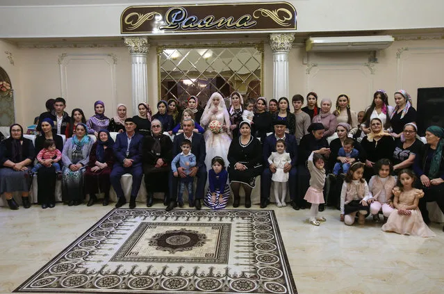 Both families' members pose for a group photograph with the bride during a traditional Chechen wedding ceremony in Grozny, Chechnya, Russia on November 24, 2016. (Photo by Valery Sharifulin/TASS)