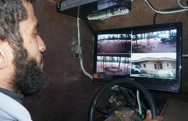 A Syrian rebel uses a videogame controller to activate the machine gun of Sham 2, a homemade armored vehicle made by the rebels' Al-Ansar brigade, in Bishqatin, 4 km west of Aleppo, on December 8, 2012. (Photo by Herve Bar/AFP Photo)