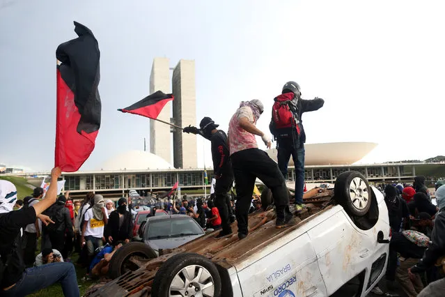 Anti-government demonstrators gesture atop a press car of Tv Record as they attend a demonstration against a constitutional amendment, known as PEC 55, that limits public spending, in front of Brazil's National Congress in Brasilia, Brazil November 29, 2016. (Photo by Adriano Machado/Reuters)