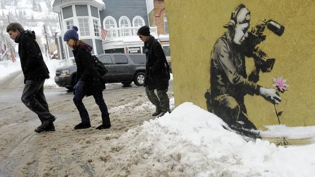 In this January 22, 2010 file photo, festivalgoers walk up Main Street past a design by graffiti artist Banksy during the Sundance Film Festival in Park City, Utah. The 2016 Sundance film festival runs from January 21-31. (Photo by Chris Pizzello/AP Photo)