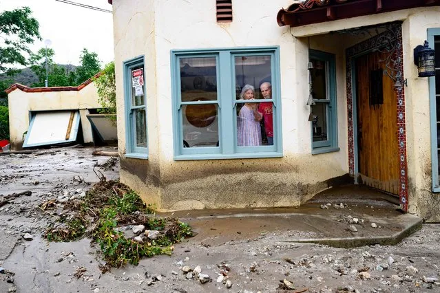 Residents trapped in their home peer out a window while waiting for help in Yucaipa, California on August, 21, 2023. Tropical Storm Hilary drenched Southern California with record rainfall, shutting down schools, roads and businesses before edging in on Nevada on August 21, 2023. California Governor Gavin Newsom had declared a state of emergency over much of the typically dry area, where flash flood warnings remained in effect until this morning. (Photo by Josh Edelson/AFP Photo)