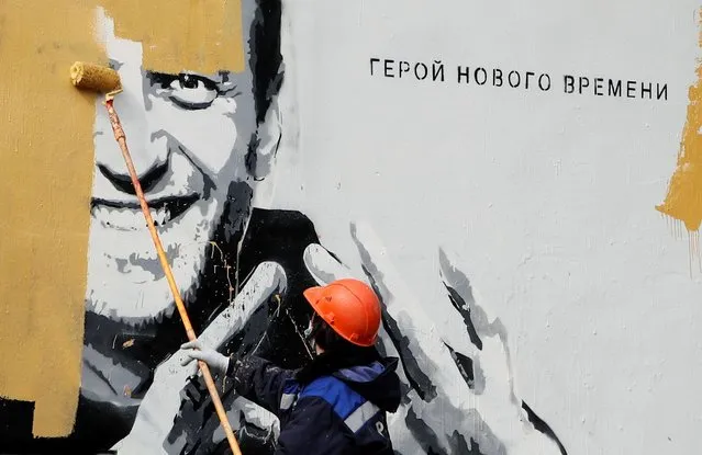 A worker paints over a graffiti depicting jailed Russian opposition politician Alexei Navalny in Saint Petersburg, Russia on April 28, 2021. The graffiti reads: “The hero of the new age”. (Photo by Anton Vaganov/Reuters)