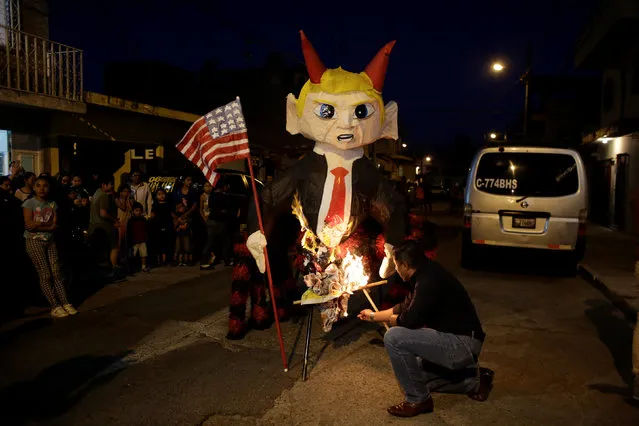 A man sets on fire a pinata representing U.S. President-elect Donald Trump as a devil during the traditional Burning of the Devil festival, ahead of Christmas in Guatemala City, Guatemala December 7, 2016. (Photo by Luis Echeverria/Reuters)