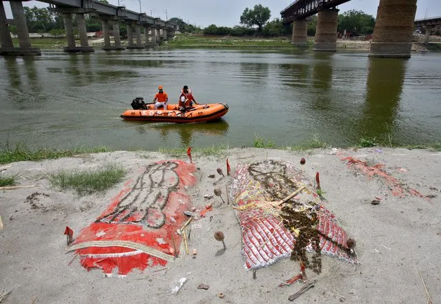 Members of State Disaster Response Force (SDRF) patrol in the waters of Ganges river past shallow sand graves of people, some of which are suspected to have died from the coronavirus disease (COVID-19), on the banks of the river Ganges in Phaphamau on the outskirts of Prayagraj, India, May 21, 2021. (Photo by Ritesh Shukla/Reuters)