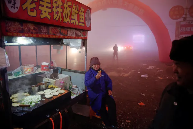 A food vendor waits for customers as heavy smog blankets Shengfang, in Hebei province, on an extremely polluted day with red alert issued, China December 19, 2016. (Photo by Damir Sagolj/Reuters)