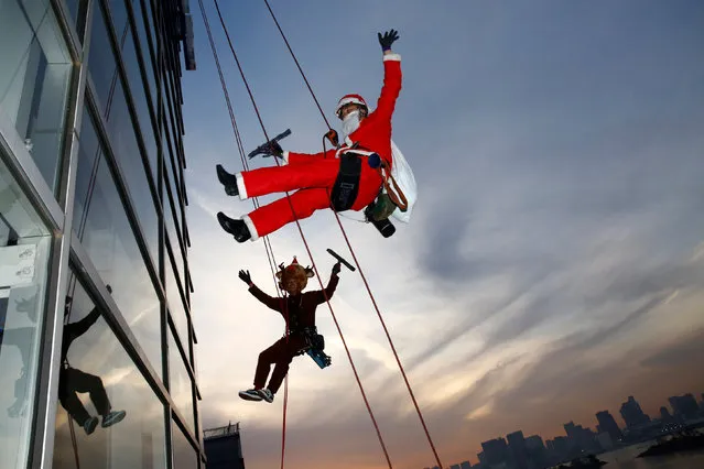 Window cleaners dressed as Santa Claus and a reindeer pose for photographers as they clean a glass window at an event to celebrate the upcoming Christmas at DECKS Tokyo Beach in Tokyo, Japan, December 21, 2016. (Photo by Kim Kyung-Hoon/Reuters)