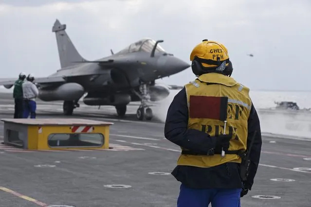 A “Yellow dog” flight deck director holds his “stop flag” as he waits for a Rafale fighter jet to be readied for a catapult take off from France's Charles de Gaulle aircraft carrier for a mission in the Gulf, January 29, 2016. (Photo by Philippe Wojazer/Reuters)