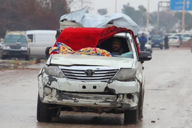 A man drives a vehicle with a blanket used instead of a broken windshield at insurgent-held al-Rashideen in the province of Aleppo, Syria December 22, 2016. (Photo by Ammar Abdullah/Reuters)