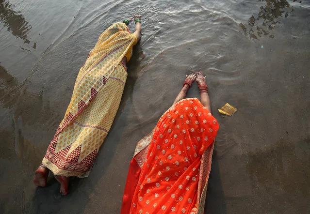 Hindu women lie as they worship the Sun god in the waters of the Arabian Sea during the religious festival of Chhath Puja in Mumbai, India, November 13, 2018. (Photo by Francis Mascarenhas/Reuters)